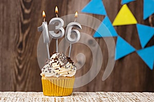 Birthday card with candle number 136 - Wooden background with pennants