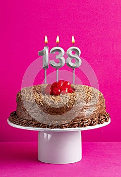 Birthday card with candle number 138 - Chocolate cake on pink background