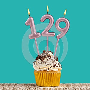 Birthday card with number 129 candle on aquamarine background