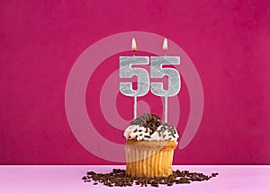 Birthday celebration with candle number 55 - Chocolate cupcake on pink background
