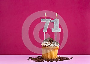 Birthday celebration with candle number 71 - Chocolate cupcake on pink background