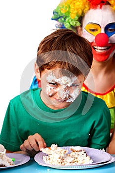 Birthday child clown eating cake with boy together. Kid with messy face.