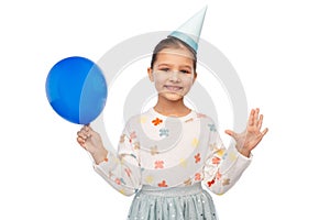 happy girl in birthday party hat blowing balloon