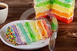 Birthday colorful rainbow cake with cup of coffee and knife