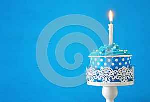 Birthday concept with cupcake and one candle on wooden table