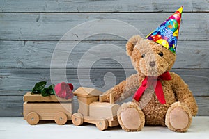 Birthday concept, teddy bear in party cap and wooden toy train