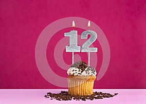 Birthday cupcake with candle number 12 - Birthday card on pink background