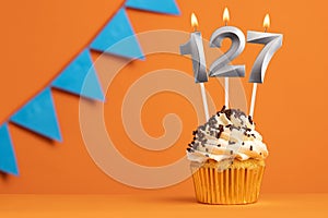 Birthday cupcake with candle number 127 - Orange background