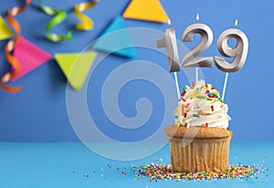 Birthday cupcake with candle number 129 - Blue background