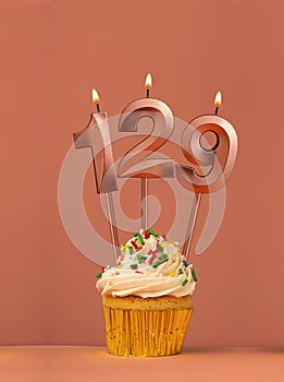 Birthday cupcake with candle number 129 - Coral fusion background