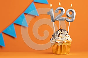 Birthday cupcake with candle number 129 - Orange background