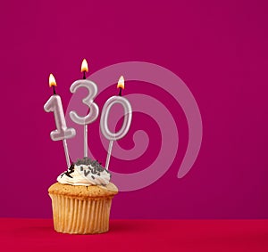 Birthday cupcake with candle number 130 - Rhodamine Red foamy background
