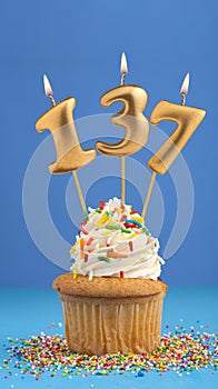 Birthday cupcake with candle number 137 - Blue background