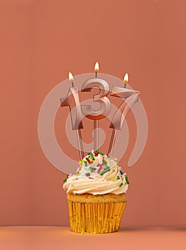 Birthday cupcake with candle number 137 - Coral fusion background