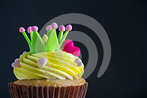Birthday cupcake in front of a black background Cupcake with yellow cream and heart for love valentines.