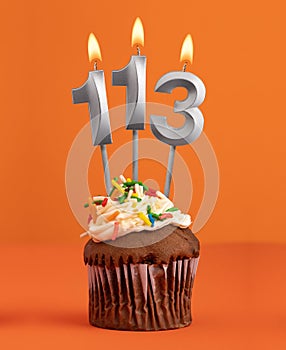 Birthday cupcake with number 113 candle - Orange color background