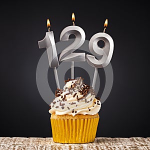 birthday cupcake with number 129 candle - Celebration on dark background