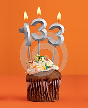 Birthday cupcake with number 133 candle - Orange color background