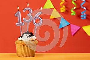 Birthday cupcake with number 136 candle - Sparkling orange background with bunting