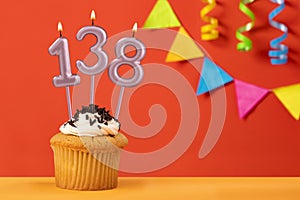 Birthday cupcake with number 138 candle - Sparkling orange background with bunting