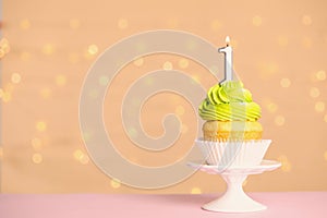 Birthday cupcake with number  candle on stand against festive lights, space for text