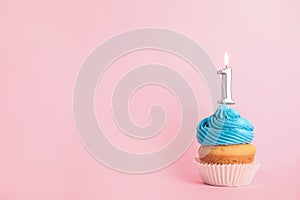 Birthday cupcake with number one candle on pink background