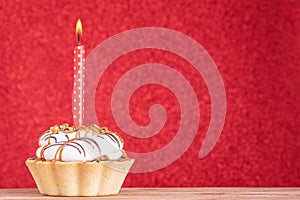 Birthday cupcake on red background with copy space. Caramel cupcake with one red candle