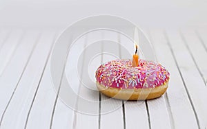 Birthday donut with pink glaze and colorful candies and burning