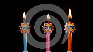 Birthday festive candles in form of sun in sunglasses isolated on black background