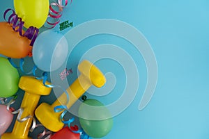 Birthday flat lay composition with gym dumbbells, balloons, ribbons and copy space.