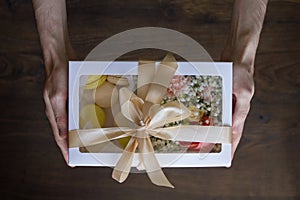 Birthday gift white box with sweet multi-colored french freshly baked macaroons and a bouquet of roses, ranunculus and cloves.