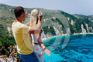 Birthday gift. Young man closing hes girlfriend eyes in front of gorgeous seascape panorama of blue lagoon. Couple love