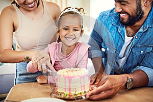 A birthday girl has to cut her cake. a little girl celebrating a birthday with her parents at home.