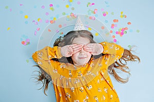 Birthday girl lies on a floor covering eyes with hands