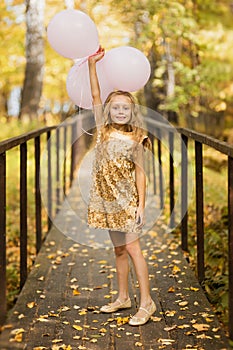 Birthday - happy girl with balloons on a path in the autumn forest. Happy childhood