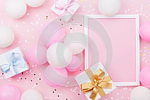 Birthday mockup with frame, gift box, pastel balloons and confetti on pink table top view. Flat lay composition.