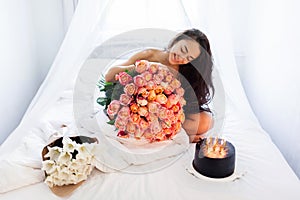 Birthday morning of young woman with huge bouquet of roses and tasty cake