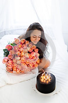 Birthday morning of young woman with huge bouquet of roses and tasty cake