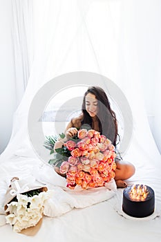 Birthday morning of young woman with huge bouquet of roses and tasty cake