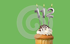 Birthday with number 112 candle and cupcake - Anniversary card on green color background