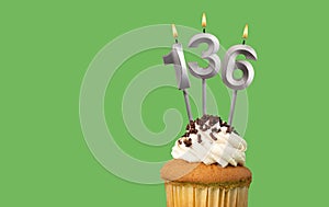 Birthday with number 136 candle and cupcake - Anniversary card on green color background