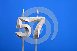 Birthday number 57 - Candle lit on blue background