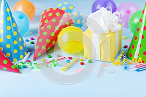 Birthday party background with gift or present box, colorful balloons, confetti, carnival cap and streamer. Holiday supplies