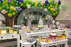 Birthday party decoration with tables, balloons, candies and cake.