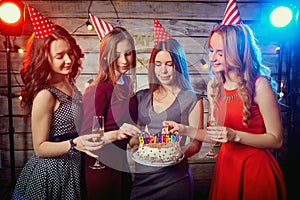 Birthday party girlfriends. Women light candles on the cake with