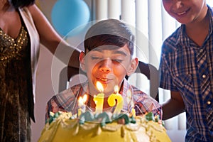 Birthday Party With Happy Latino Boy Blowing Candles On Cake