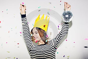 Birthday party, new year carnival. Young smiling woman on white background celebrating brightful event, wears stripped