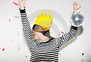 Birthday party, new year carnival. Young smiling woman on white background celebrating brightful event, wears stripped