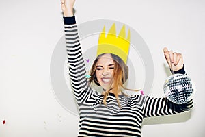 Birthday party, new year carnival. Young smiling woman on white background celebrating brightful event, wears stripped