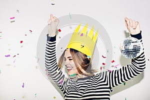 Birthday party, new year carnival. Young smiling woman on white background celebrating brightful event, wears stripped